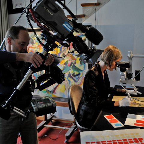 Chef-Restauratorin Iris Winkelmeyer begutachtet für unsere Kamera einen Farbtupfer von Kandinsky.